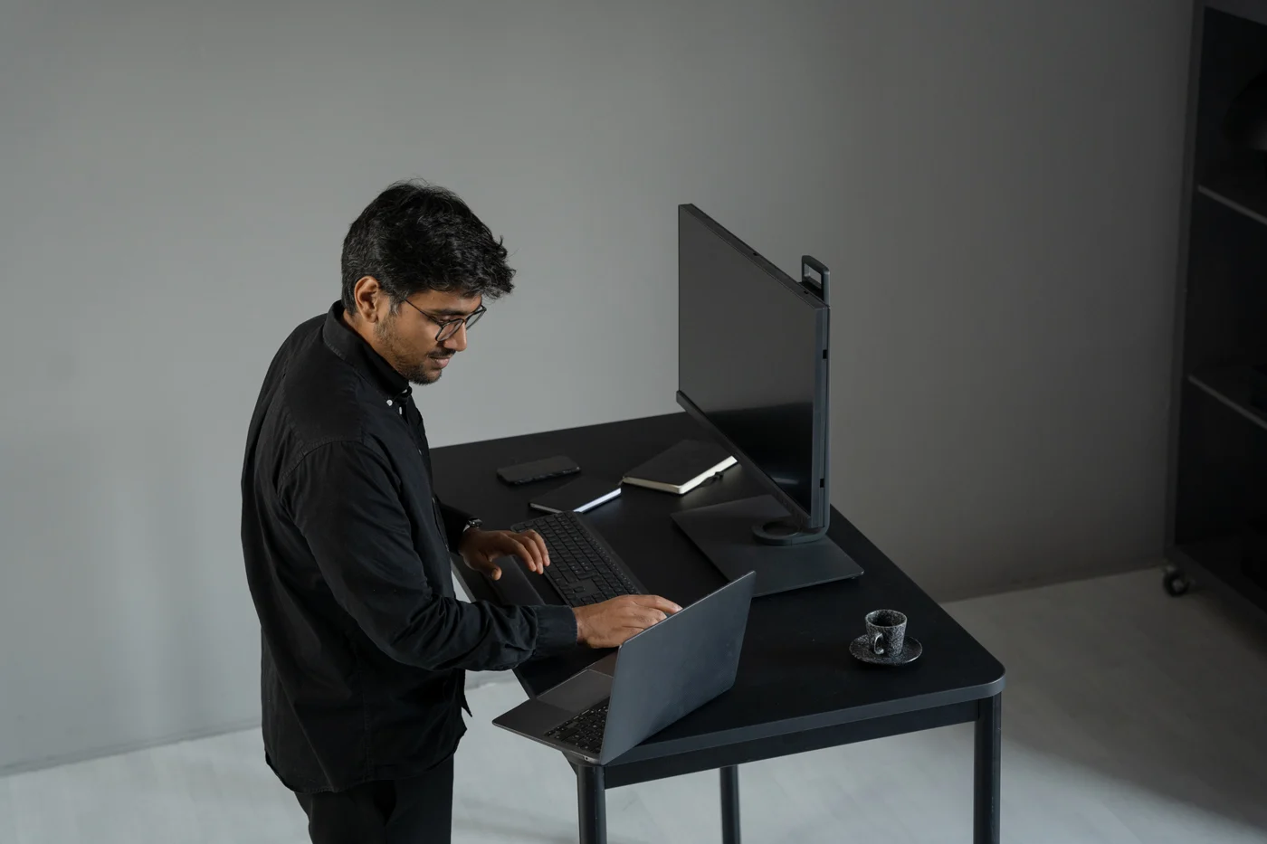 Computer specialist working at a desk with a laptop and monitor